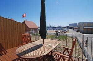 a wooden table and chairs on a deck with an umbrella at Skagen Apartment in Skagen