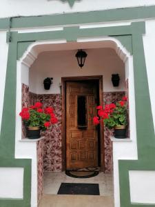 a front door of a house with red flowers at La Casa de Colores in Sariego