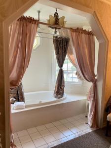 a bathroom with a tub with curtains and a window at The Cypress Inn in Conway