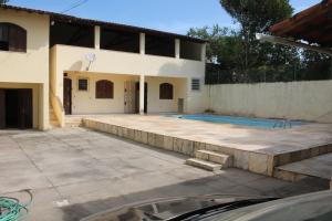 un patio trasero con piscina y una casa en Casa muito espaçosa privativa com Piscina, Churrasqueira e área gourmet en Araruama