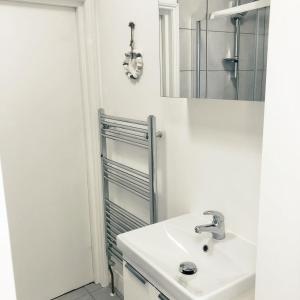 een witte badkamer met een wastafel en een spiegel bij Southside Street Apartments in Plymouth