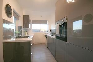 a kitchen with stainless steel appliances and a clock on the wall at Charming 3-Bed House in Whitwell village in Worksop