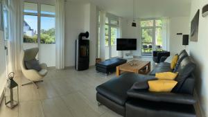 a living room with a black leather couch and chairs at 5 Sterne Luxusdomizil im Dünenland in Ostseebad Karlshagen