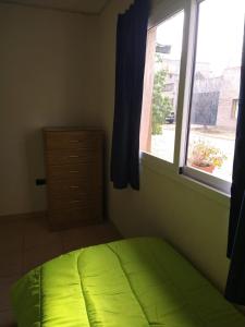 a bedroom with a green bed and a window at Casa La Comarca in San Rafael