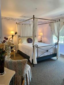 um quarto com uma cama de dossel e uma cadeira em The Cypress Inn em Conway