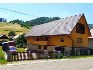 ein großes Holzhaus mit einem Zaun davor in der Unterkunft Chalupa Praženica in Liptovské Revúce