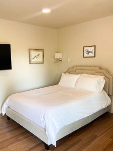 a bedroom with a bed with white sheets and a tv at Spruce Lodge in Seward