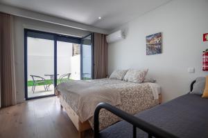une chambre avec deux lits et un balcon avec une table dans l'établissement Gravito 53 Apartments by Home Sweet Home Aveiro, à Aveiro