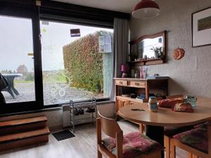ein Wohnzimmer mit einem Tisch und einem großen Fenster in der Unterkunft Appartement idéal près de Durbuy / Ideaal appartement nabij Durbuy / Ideal apartment near Durbuy in Hotton