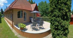a house with a patio with chairs and an umbrella at Vica Apartman in Balatonberény