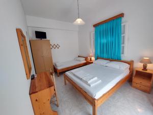 1 dormitorio con 1 cama, TV y ventana en ALKYONI STUDIOS, en Amorgós