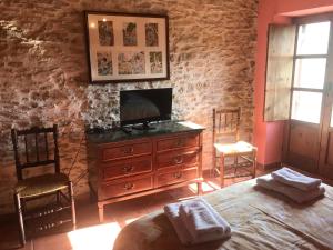 1 dormitorio con tocador de madera y TV. en Masia MATUTANO en Villafranca del Cid