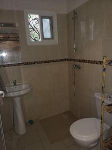 ein Bad mit einem WC, einem Waschbecken und einem Fenster in der Unterkunft Keur Baboune in M'bour