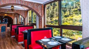 a restaurant with red chairs and tables and a large window at Aurocher Ourika Oukaimeden in Oukaïmeden