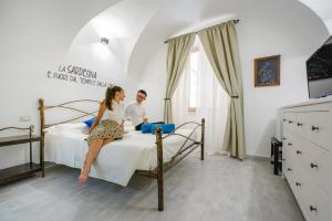 a man and a woman sitting on a bed at Casa Mirto in Bosa