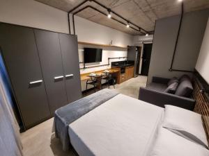um quarto com uma cama, um sofá e uma televisão em APTO Studios em Itajaí