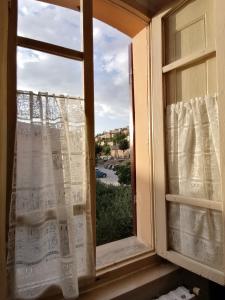 una ventana con cortinas y vistas a la calle en La Musa di Spello, en Spello