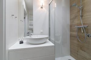 a white bathroom with a sink and a shower at Apartament Muszelka Jantar TriApart in Jantar