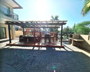 a patio with a wooden pergola and a table and chairs at Oyster Guest House in Durban