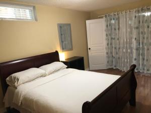 um quarto com uma cama com lençóis brancos e uma janela em Spacious 2 Bedroom guest suite em Toronto