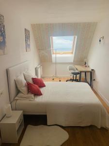a bedroom with a bed with red pillows and a window at Apartamentos LAMAROSA -ATICO ,Vistas al Mar Cantabrico PARKING in Burela de Cabo