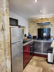 a kitchen with a stainless steel refrigerator at Le Clos des Figuiers - 3 Gîtes de caractère in Duravel