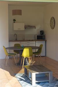 uma cozinha com uma mesa e quatro cadeiras e uma mesa e uma mesa em Villa Saint Fort - Résidence Services em Saint-Fort