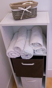 uma prateleira branca com toalhas e um cesto em Villa Saint Fort - Résidence Services em Saint-Fort