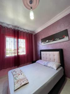 a bedroom with a bed with red walls at Apartement 3 residence oulad touimi in Martil