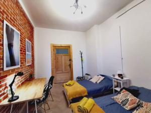 1 dormitorio con 2 camas, escritorio y pared de ladrillo en Smart Hostel Olsztyn, en Olsztyn