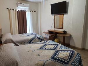 1 dormitorio con 2 camas, espejo y TV en HOTEL PLAZA, en La Paz