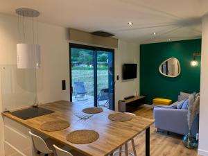 cocina y sala de estar con mesa de madera en Charmant logement entre Lac et Montagne en Rochebrune