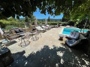 eine Terrasse mit Liegestühlen und einem Pool in der Unterkunft La Bergerie Barbebelle in Villecroze