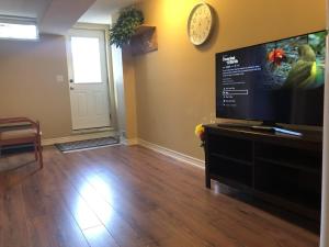 a living room with a flat screen tv and a clock at Spacious 2 Bedroom guest suite in Toronto