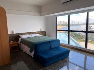a bedroom with a bed and a chair and a large window at Flat no Tropical - Linda Vista da Praia in Manaus