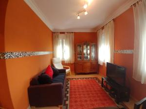a living room with orange walls and a couch and a tv at A casa de Xues in Pontevedra