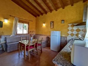 a kitchen and living room with a table and a couch at Las Cabañas de La Vera in Aldeanueva de la Vera