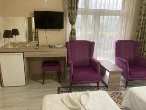 a room with purple chairs and a desk with a tv at SARIMESE OTEL in Demirci