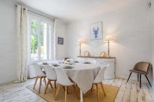 uma sala de jantar branca com uma mesa e cadeiras em The White House - Deauville em Deauville