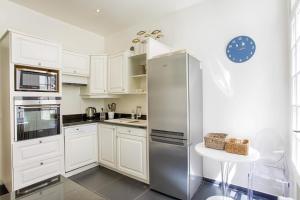 a kitchen with white cabinets and a stainless steel refrigerator at The White House - Deauville in Deauville