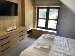a bedroom with a bed and a flat screen tv at Dom z balią na Kaszubach-Widokova in Borucino