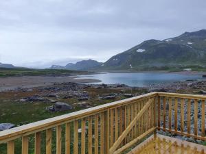 a wooden balcony with a view of a lake and mountains at Jotunheimen Arctic Domes in Beitostøl