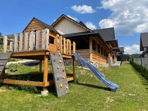 a playground with a slide in front of a house at Nase Chaty- domki z balią, termy i natura in Biały Dunajec