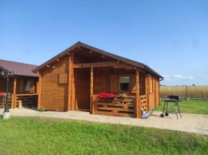 eine Blockhütte mit einem Grill davor in der Unterkunft Familijny Zakątek domki letniskowe Gąski in Gąski