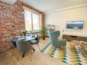 a living room with a brick wall and a table and chairs at Prestige Apartments Świętojańska in Gdynia