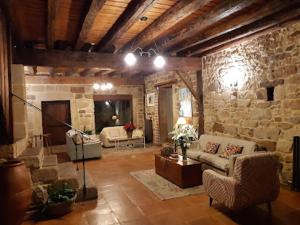 sala de estar con sofá y pared de piedra en La Casona de El Royo, en El Royo