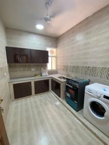 a kitchen with a washing machine and a washer at Aknan Al Saada in Salalah