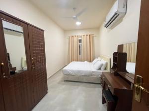 a bedroom with a bed and a television and a door at Aknan Al Saada in Salalah