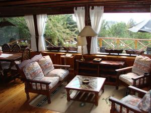 a living room with chairs and a table and windows at La mas bella vista in San Carlos de Bariloche