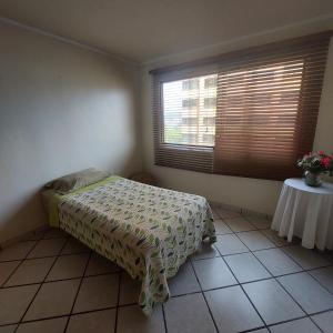 Schlafzimmer mit einem Bett, einem Tisch und einem Fenster in der Unterkunft Apartamentos Ejecutivos en Naguanagua in Naguanagua